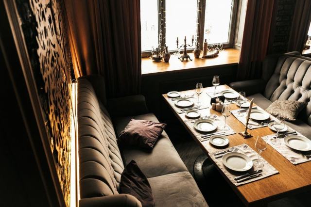 Coin repas avec banquette dans une cuisine Table en bois et banquette d'angle installées sous la fenêtre d'une cuisine
